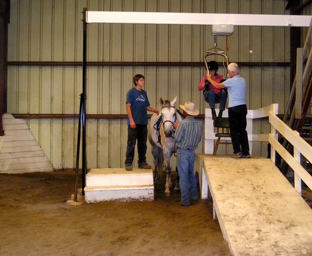 challenged rider being lifted onto a horse
